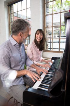 Mature couple having fun at home, playing the piano